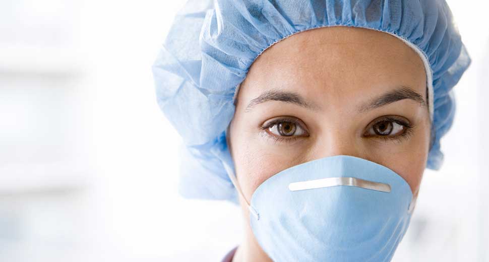 female nurse looking at camera wearing surgical mask and scrubs